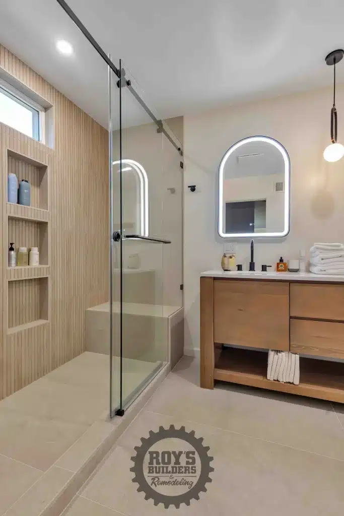 Wood vanity and glass shower beside window