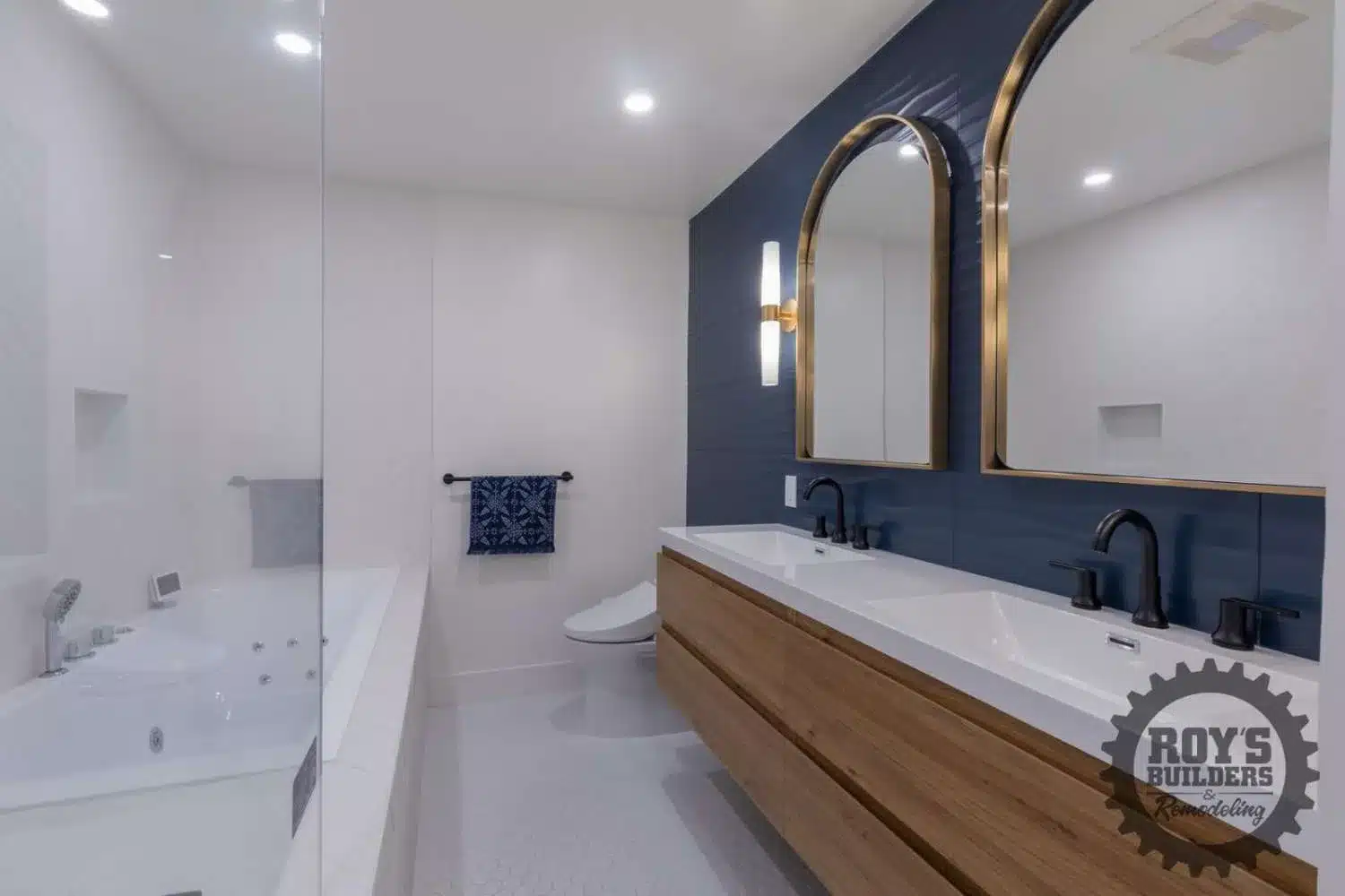 Double vanity with a wood cabinet, white countertop, two gold arch mirrors