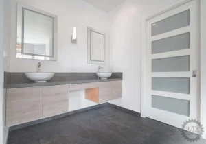 Modern bathroom with double vanity, vessel sinks, and frosted door