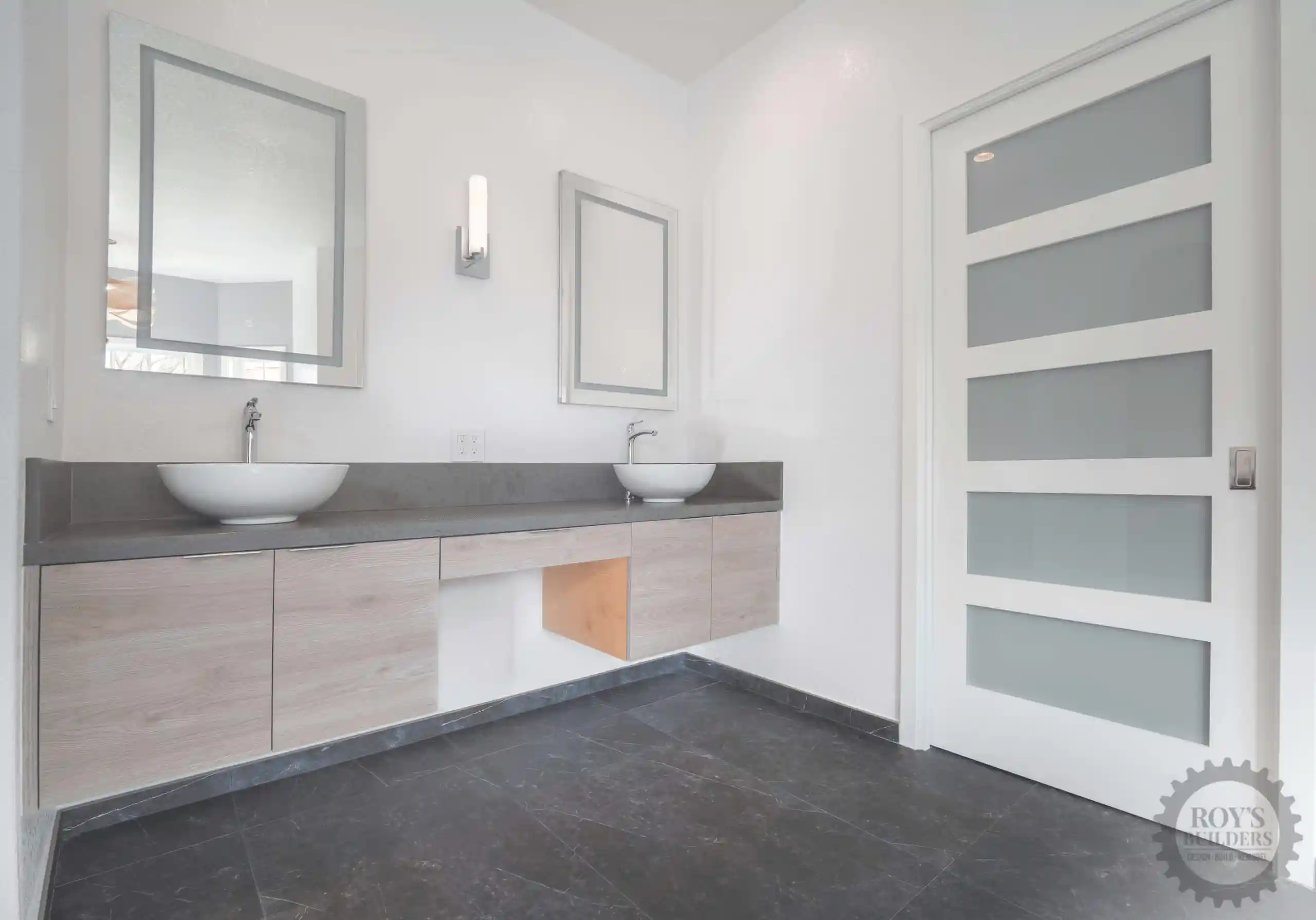Modern bathroom with double vanity, vessel sinks, and frosted door