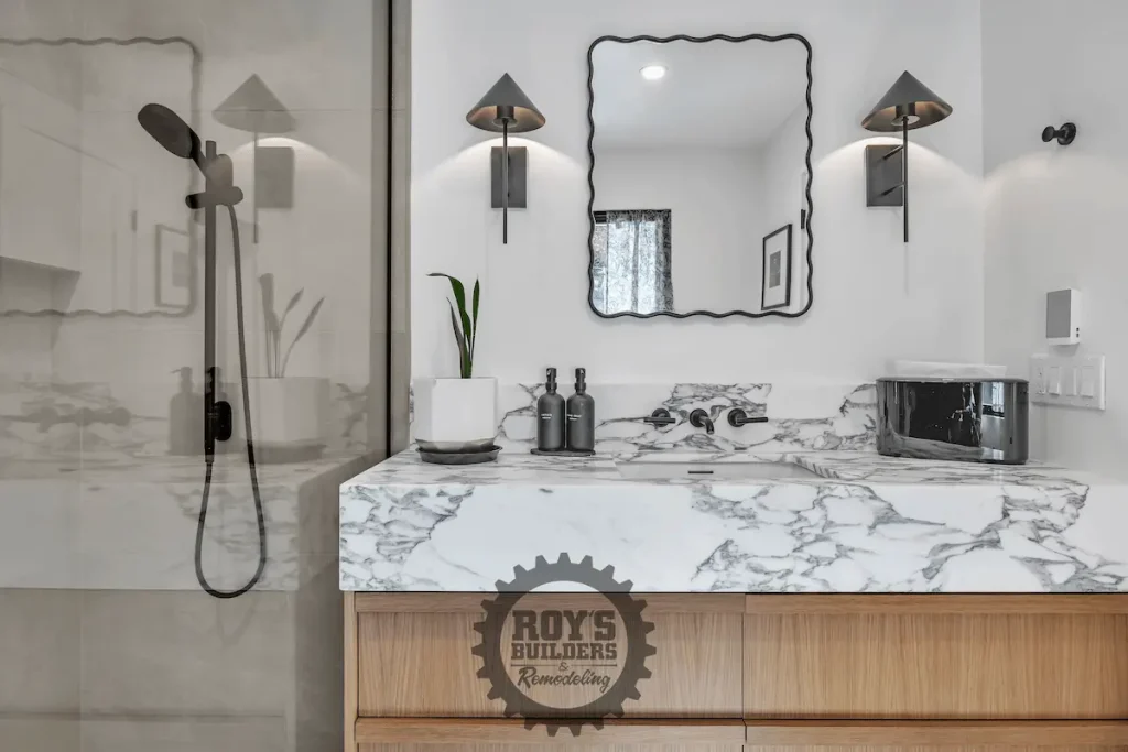 Marble-top vanity beside glass-enclosed shower