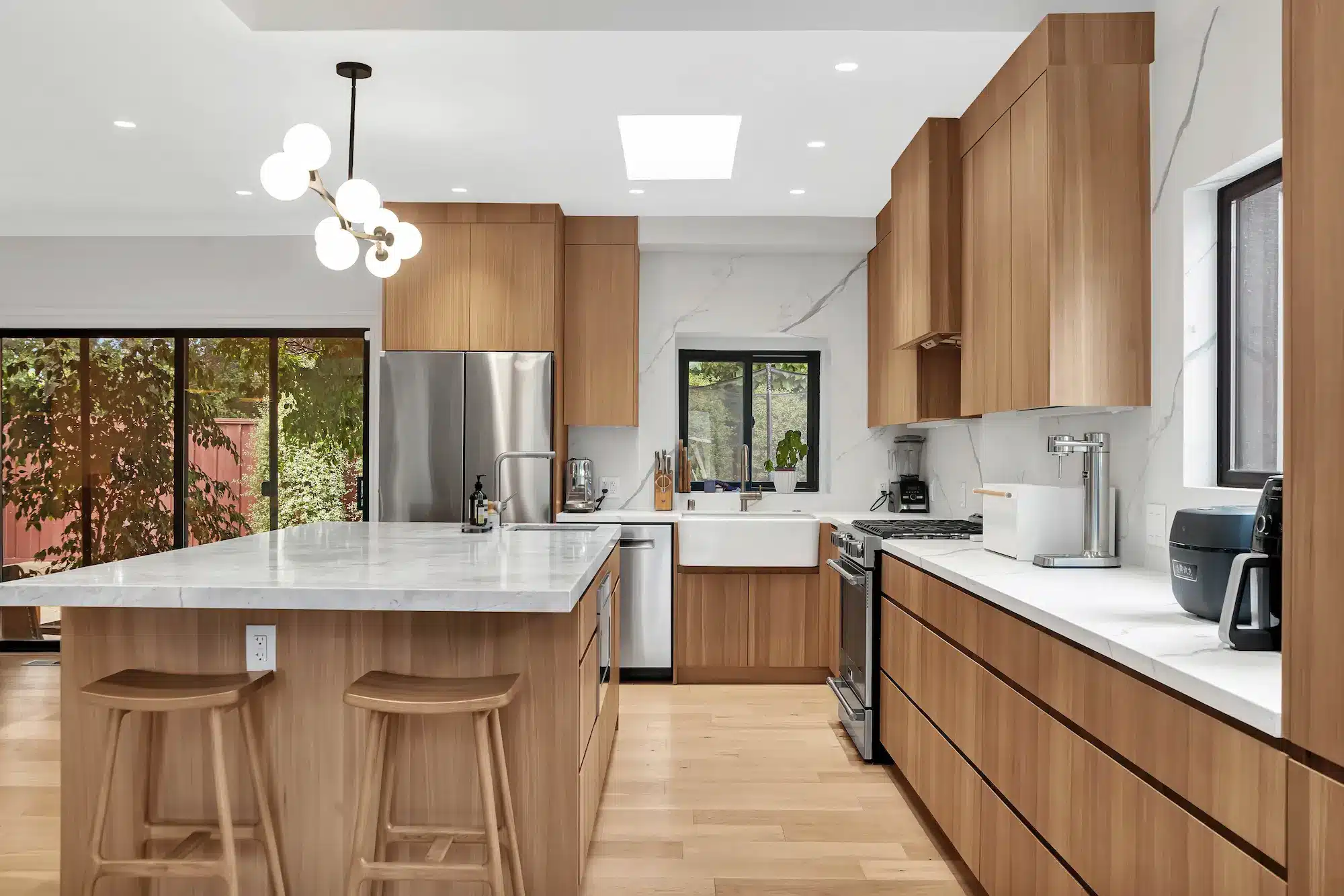 A kitchen featuring light-colored wood cabinets, a white island, and a modern branching light fixture.