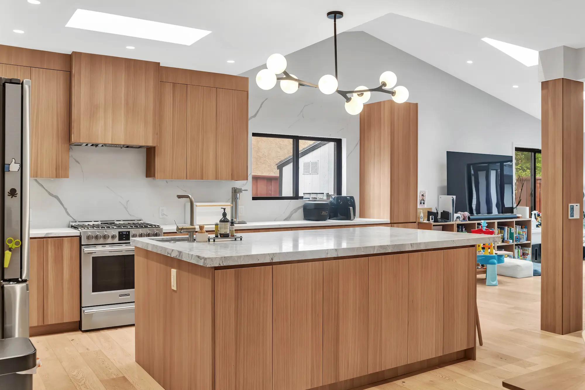 A bright kitchen with vaulted ceilings, a large wooden island, and views into an adjacent living area.