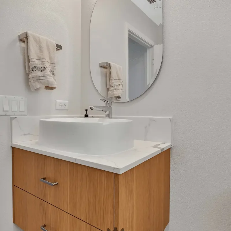 Bathroom vanity with round mirror and wooden cabinetry