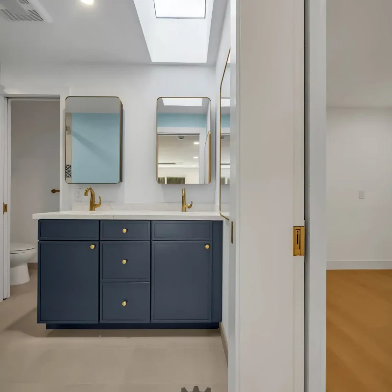 Bright bathroom with a skylight illuminating a blue double vanity.