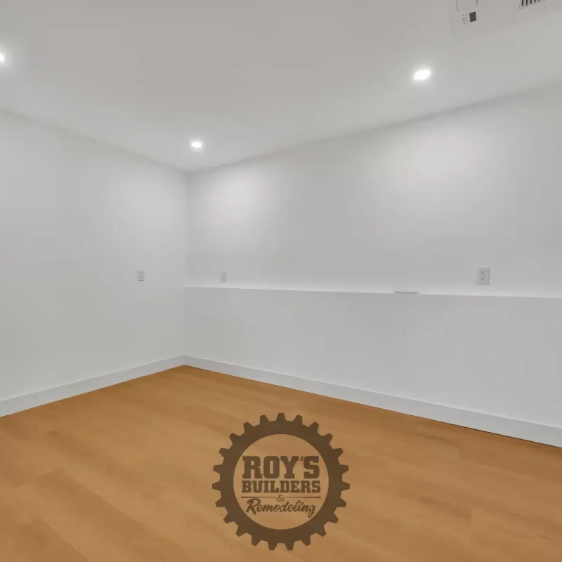Bright, empty room with white walls, simple molding, and light wood flooring.