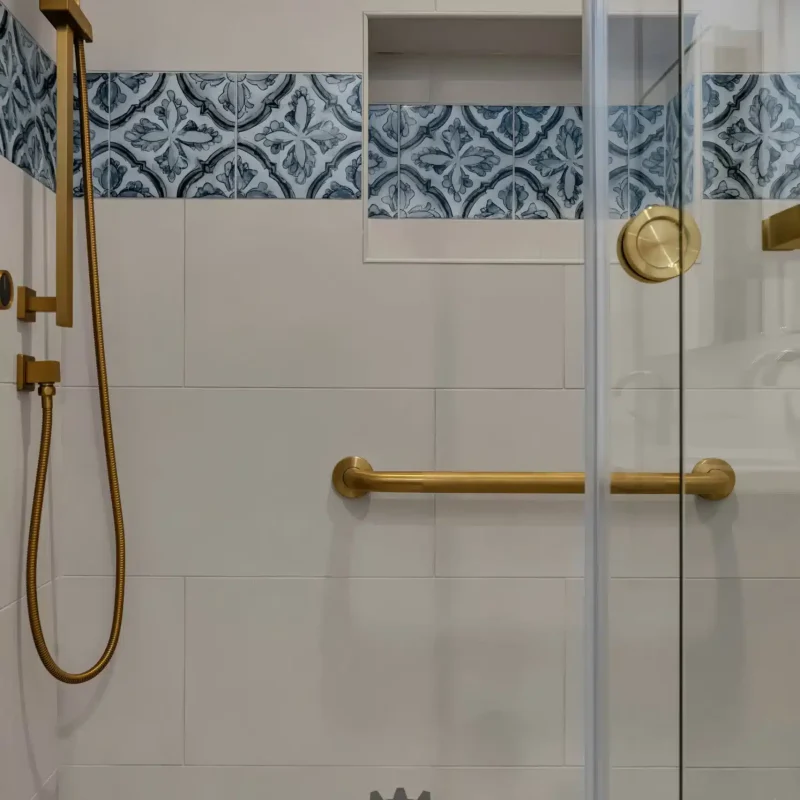 Close-up of a tiled shower niche and gold plumbing fixtures.