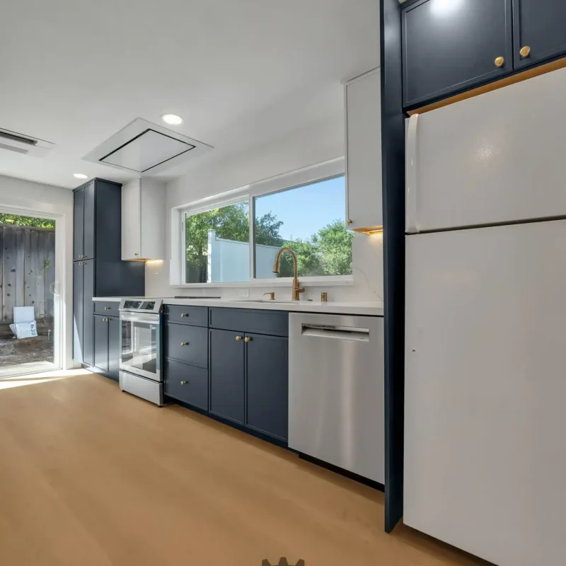 Corner view of a kitchen showing a white refrigerator next to dark blue cabinetry.