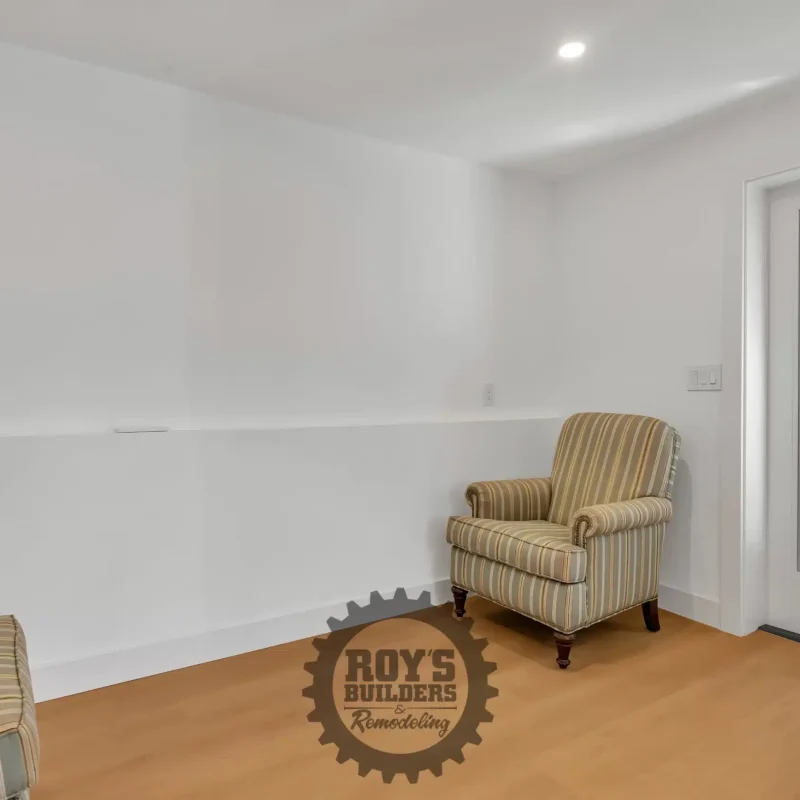 Empty room featuring a cozy armchair near a white exterior exit door.