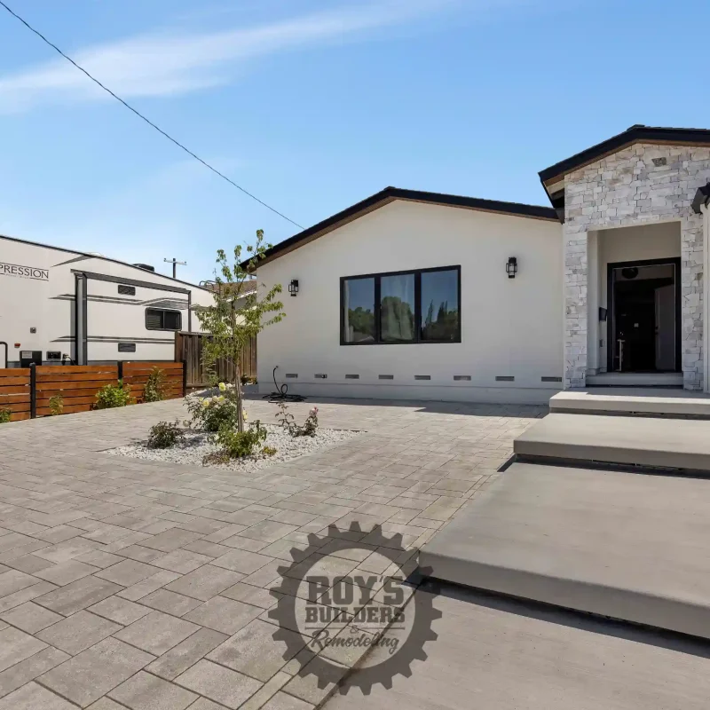 Landscaped front yard featuring a paver driveway and modern home exterior.