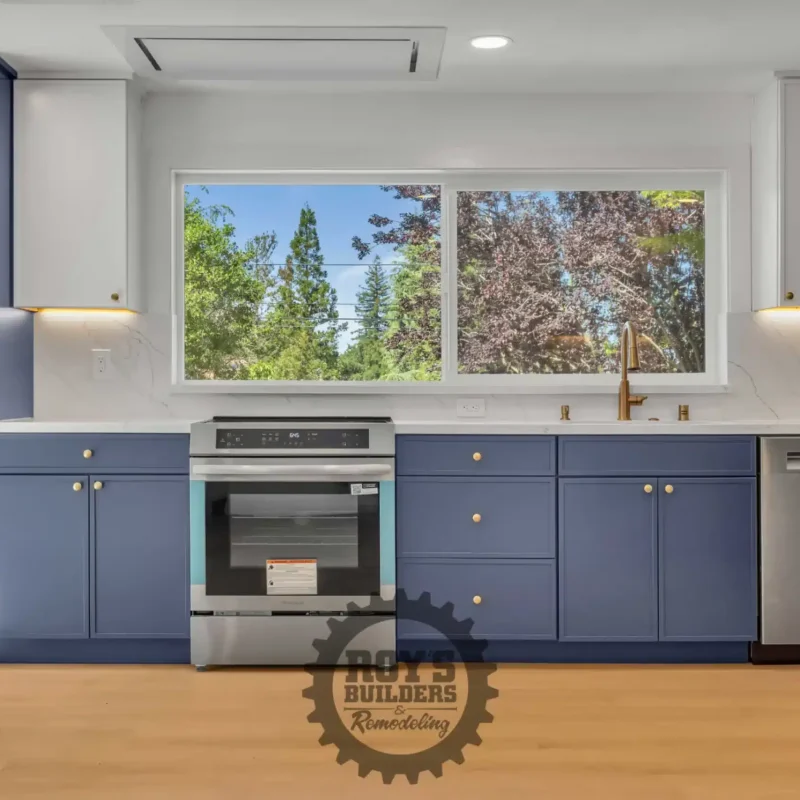 Full-length view of the kitchen counter wall with blue cabinets and stainless steel appliances.