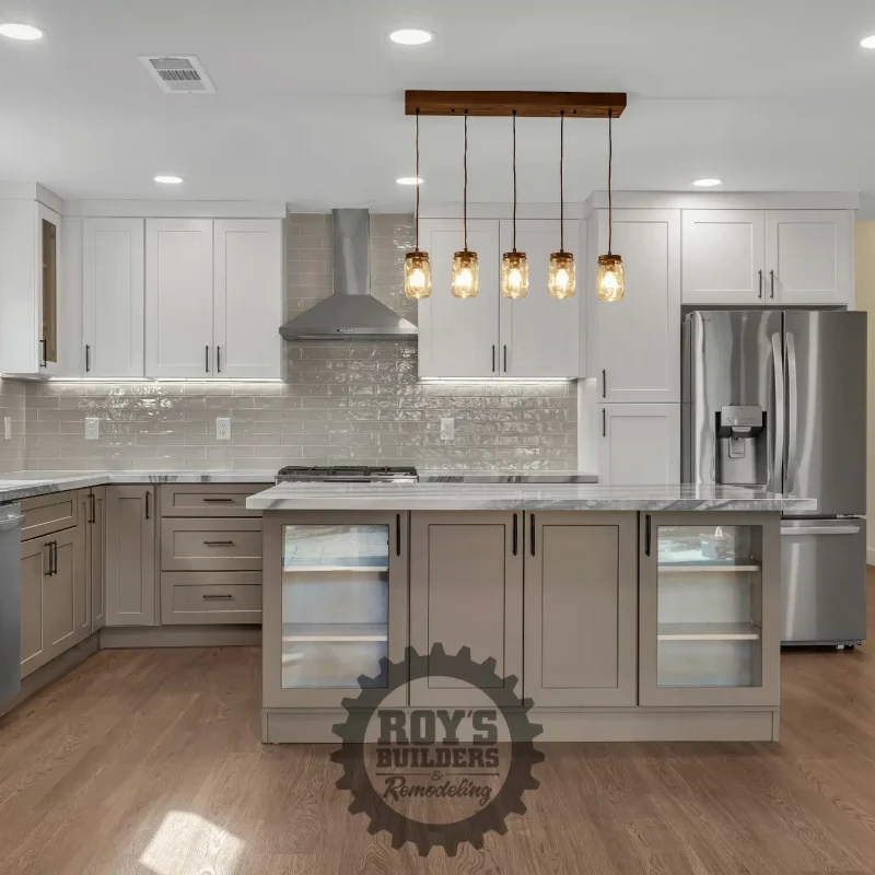 Modern kitchen remodel with custom white and beige cabinetry, stainless steel appliances, and a marble-patterned island countertop.