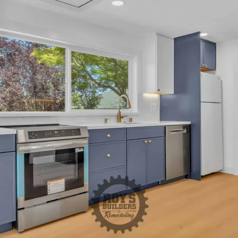 Kitchen view highlighting the sink area, a large window, and blue under-counter cabinetry.