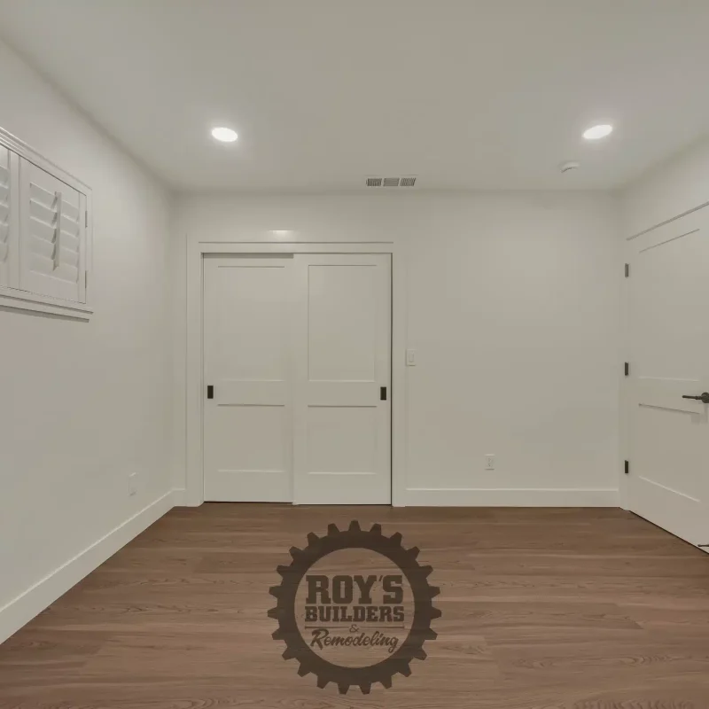 Minimalist empty bedroom with clean white walls and recessed ceiling lights.