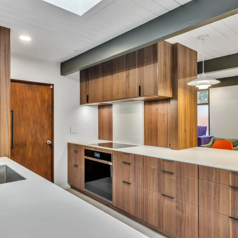 A close-up of a long wooden counter with an integrated black oven and white countertop.