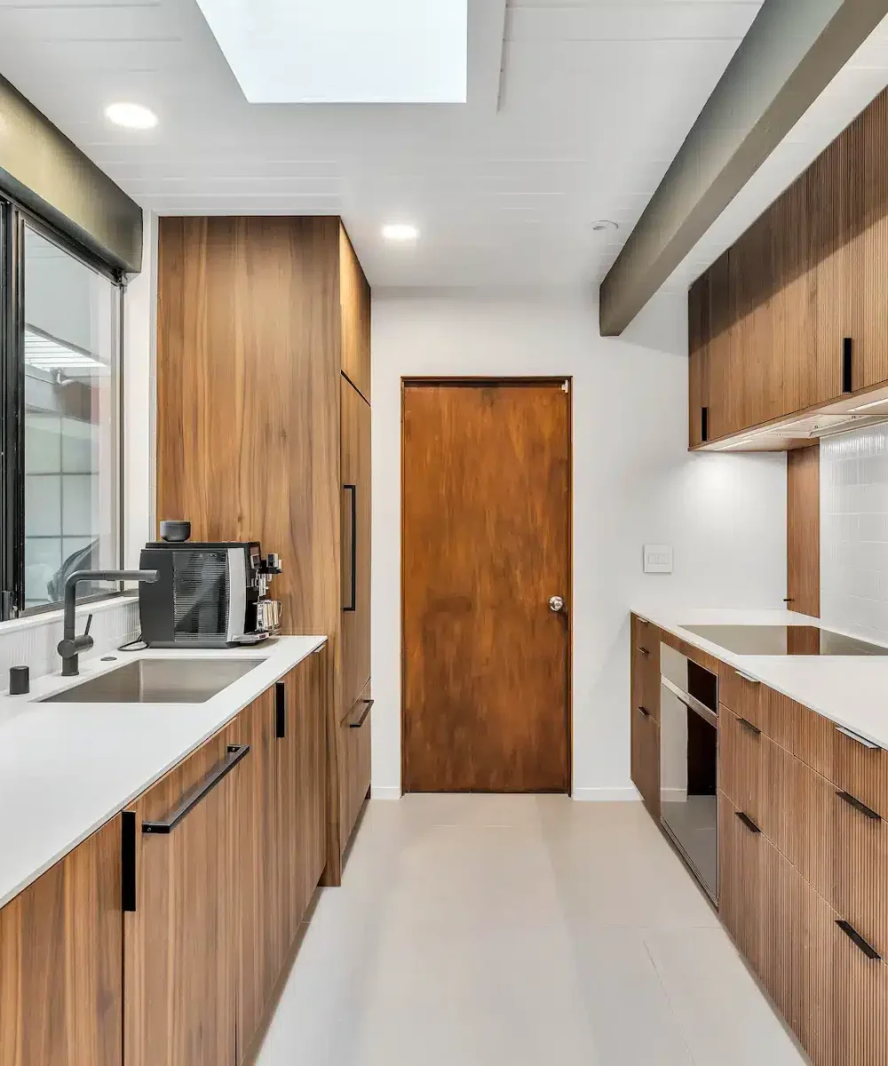 A long galley-style kitchen with wood cabinets on both sides and bright white counters.