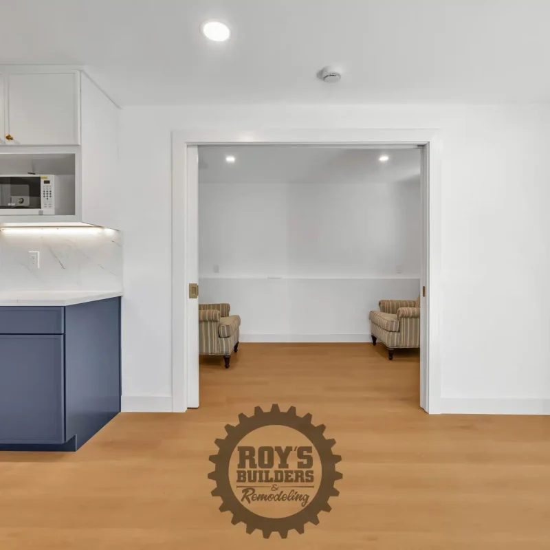 Open-concept living space with wood flooring looking into an adjacent room.