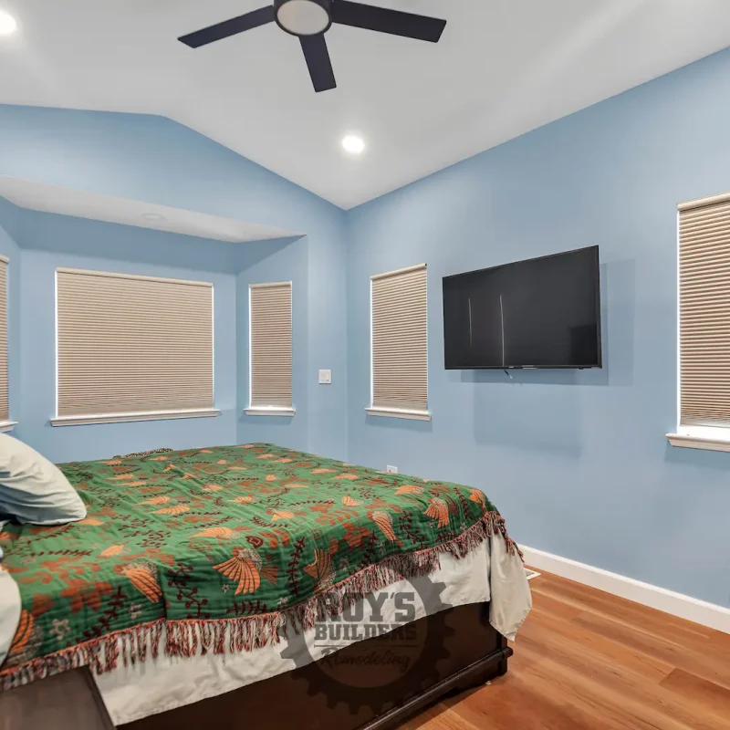 Blue bedroom with wooden floor and TV