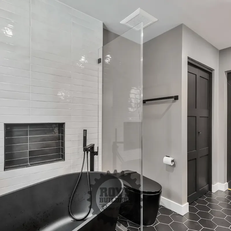 Black freestanding tub beside tiled wall