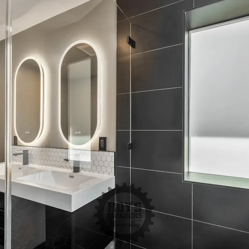 Stylish vanity with oval mirrors and tile wall