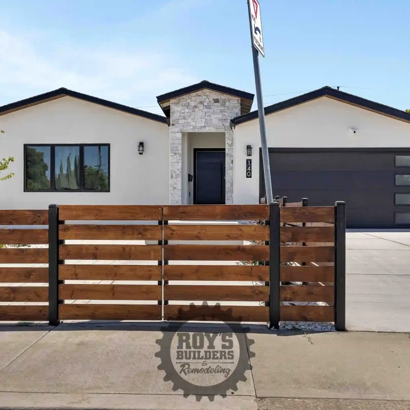 Modern single-story house exterior with a white facade and dark garage door.