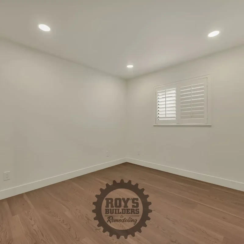 Empty bedroom interior with beige walls and recessed lighting.