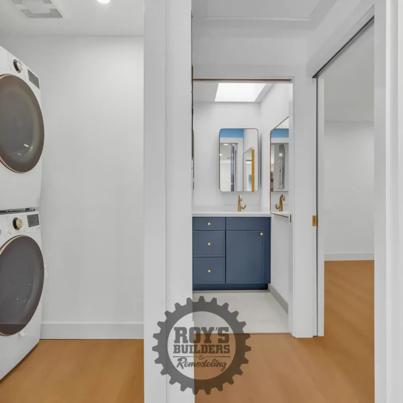 View through a hallway showing a laundry closet on the left and a bathroom vanity straight ahead.