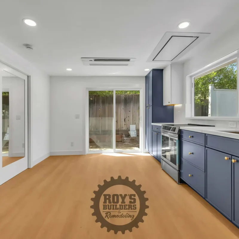 Wide view of the empty living and dining area with hardwood floors, looking towards a sliding glass door.